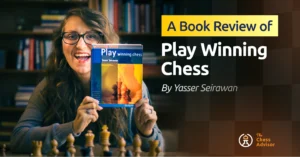 Woman holding Play Winning Chess by Yasser Seirawan, sitting behind a chessboard
